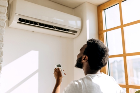 young man turning on air conditioner